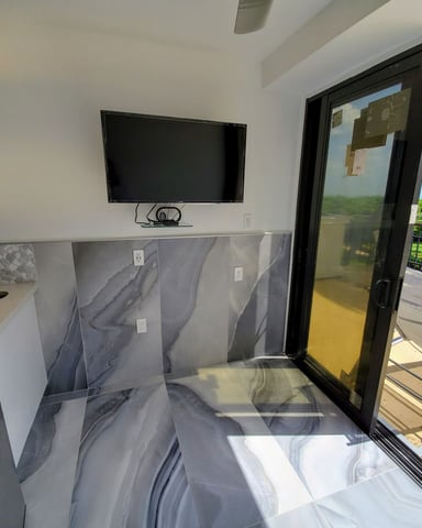 Cabana interior with Smart TV, mini-fridge, marble floors, and sliding glass door opening to the deck