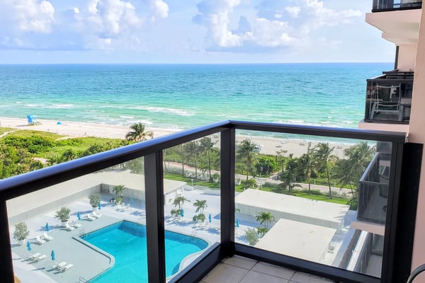 Oceanfront balcony view with pool, beach, and turquoise water below
