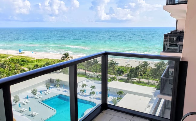 Oceanfront balcony view with pool, beach, and turquoise water below