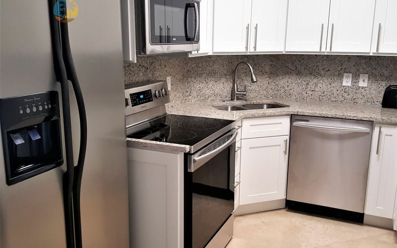 Modern kitchen with white cabinets, granite countertop, stainless steel appliances, and tile flooring.