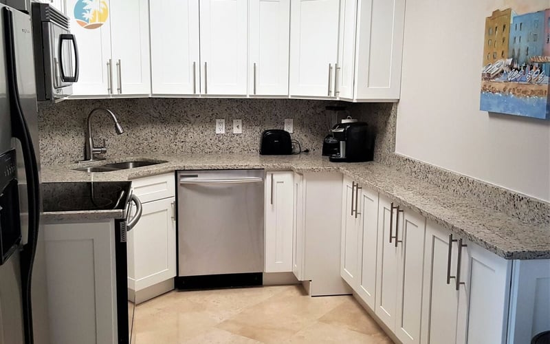 Modern kitchen with white cabinetry, granite countertops, stainless steel appliances, and tile flooring